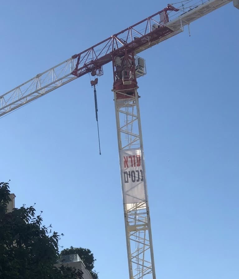 עזרא נכסים — שלט על מנוף באתר בנייה